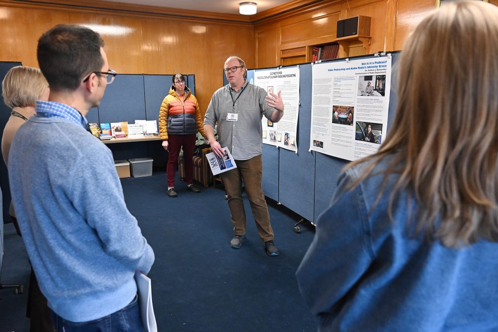 A SUNY Oneonta faculty member discusses his poster with colleagues at the 2025 Life of The Mind showcase